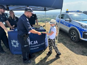 na zdjęciu widać policjanta dającego odblask dziewczynce