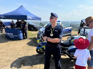 na zdjeciu widać policjanta, motocykl i radiowóz