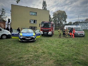 na zdjeciu widać radiowóz i wóz strażacki