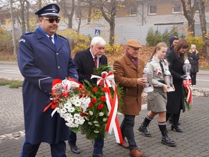 na zdjeciu widać policjanta z wieńcem i inne osoby