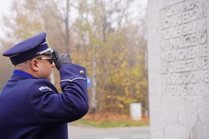 na zdjęciu widać policjanta przed pomnikiem