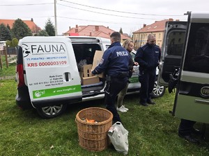 na zdjęciu widać policjanta, kobietę i dary dla zwierzat