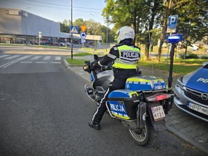 Na zdjeciu widać policjanta na motocyklu przy przejściu dla pieszych