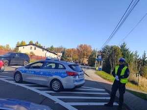 na zdjeciu widać policjanta i radiowóz przed cmentarzem