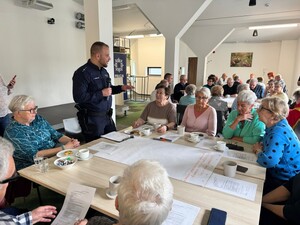 na zdjęciu widać policjanta i uczestników spotkania