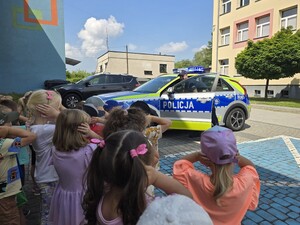 na zdjęciu widać policjanta, radiowóz i dzieci