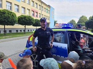 na zdjęciu widać policjanta, radiowóz i dzieci