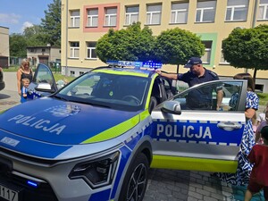na zdjęciu widać policjanta, radiowóz i dzieci